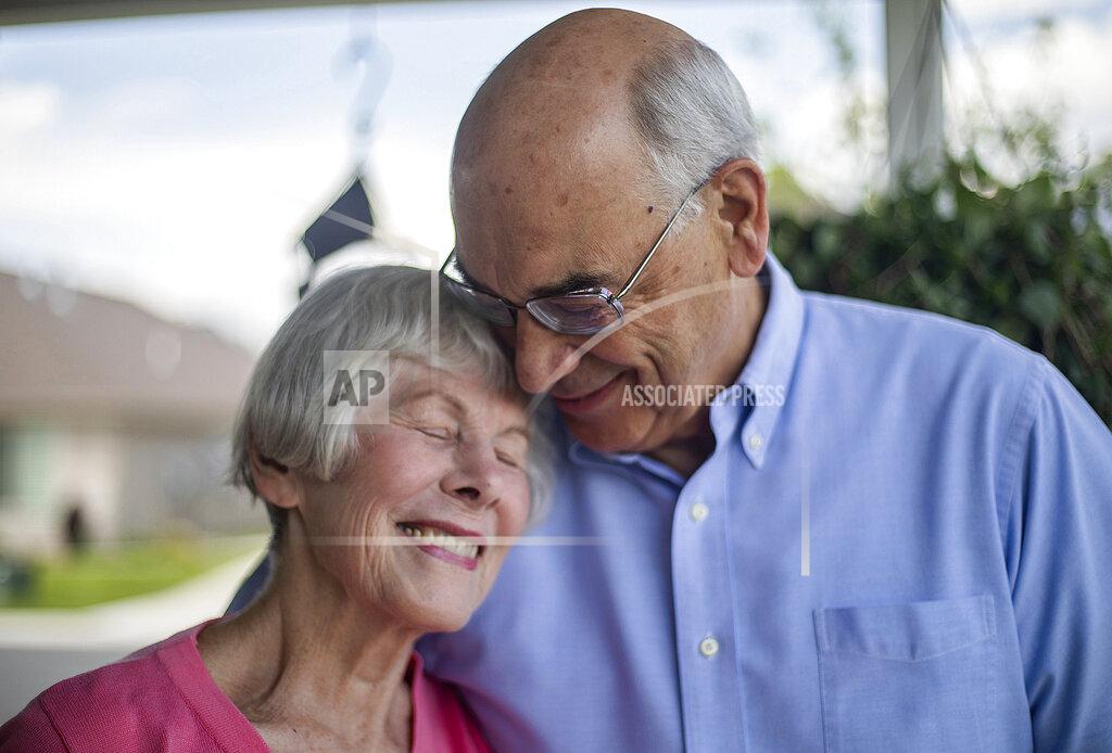 Newlyweds Ann Marcusen Bell and Enoch Bell pose for a portrait on Monday, May 11, 2020, in Kaysville, Utah. Due to COVID-19 social distancing restrictions, the couple was married in their living room while guests and the presider were present via Zoom video chat. (Ben Dorger/Standard-Examiner via AP)