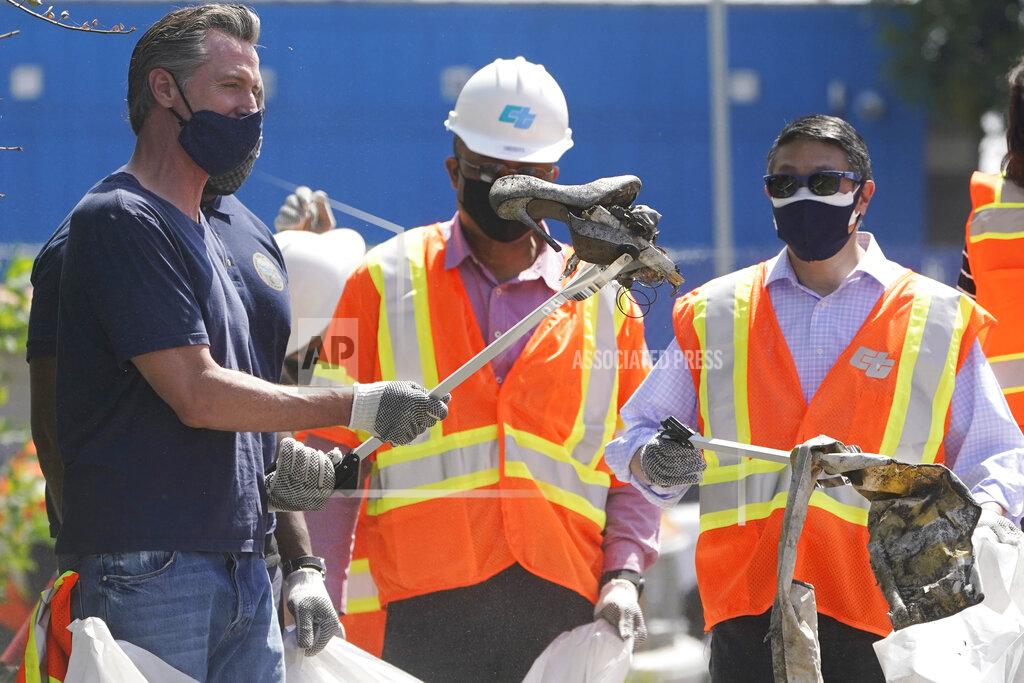 Marcio Jose Sanchez California Gov. Gavin Newsom reacts as he finds a pair of old high heel shoes as he joins a cleanup effort Tuesday, May 11, 2021, in Los Angeles. Newsom on Tuesday proposed $12 billion in new funding to get more people experiencing homelessness in the state into housing and to "functionally end family homelessness" within five years. (AP Photo/Marcio Jose Sanchez)