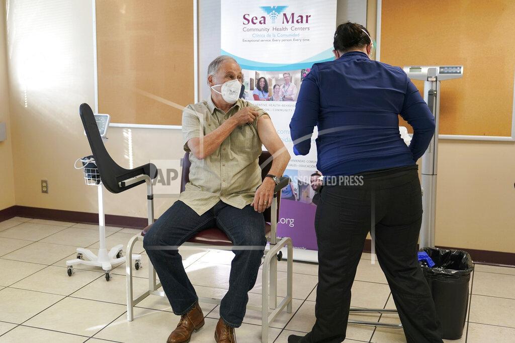 Ted S. Warren Washington Gov. Jay Inslee, left, smiles after he received the first shot of the Moderna COVID-19 vaccine, Friday, Jan. 22, 2021, from Elizabeth Smalley, right, a medical assistant at a Sea Mar Community Health Center in Olympia, Wash. Inslee's wife Trudi also received the first dose of the vaccine. (AP Photo/Ted S. Warren)