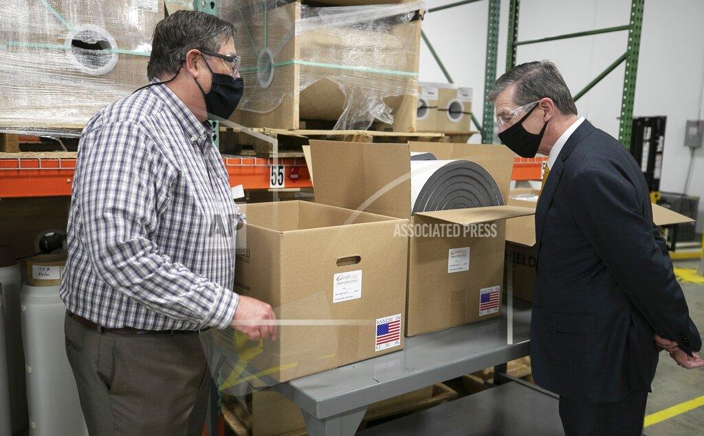Robert Willett Bright View Technologies, director of operations Michael Bobay shows North Carolina Gov. Roy Copper how the face shields the company produces are packaged for shipping on Thursday, Nov. 19, 2020 in Durham, N.C. Bright View Technologies produces optical management products and began producing face shields when the COVID-19 pandemic started. (Robert Willett/The News & Observer via AP)