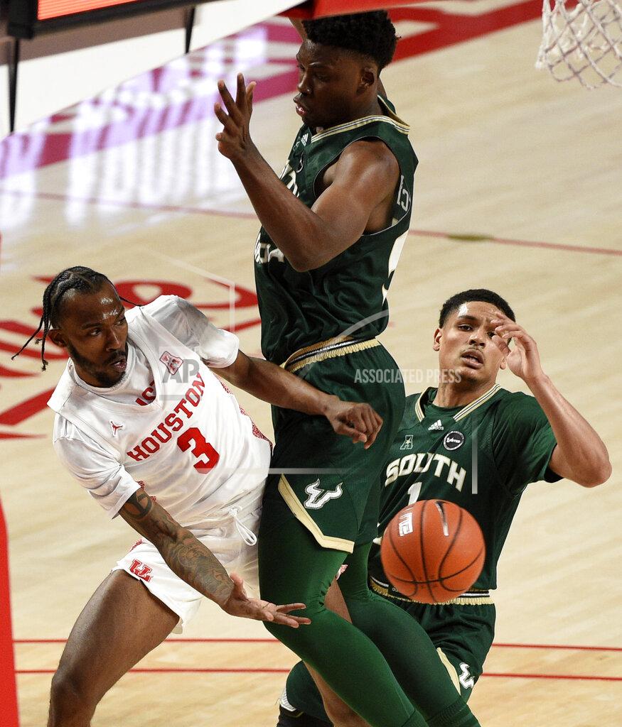 Eric Christian Smith Houston guard DeJon Jarreau (3) passes the ball around South Florida center Russel Tchewa, center, during the second half of an NCAA college basketball game, Sunday, Feb. 28, 2021, in Houston. (AP Photo/Eric Christian Smith)