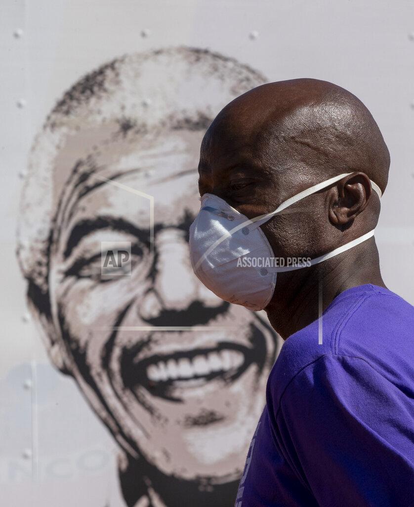 Themba Hadebe A man wearing a face mask walks past a portrait of former South African president Nelson Mandela on a mobile clinic at Lenasia South, south Johannesburg, South Africa, Tuesday, April 21, 2020, during a campaign aimed to combat the spread of the COVID-19 Coronavirus. (AP Photo/Themba Hadebe)