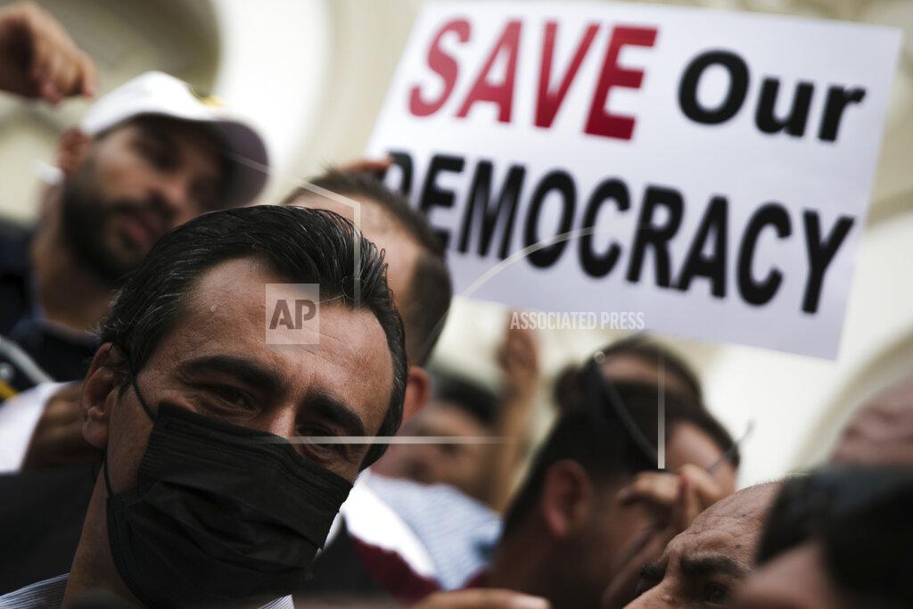 Riadh Dridi Tunisian constitutional law professor Jaouhar Ben Mbarek, left, attends a protest against Tunisian President Kais Saied, Saturday, Sept. 18, 2021 in Tunis. In July Tunisian President Kais Saied fired the country's prime minister and froze parliament's activities after violent demonstrations over the country's pandemic and economic situation. The movement made by Saied was considered by his opponents as a coup. (AP Photo/Riadh Dridi)