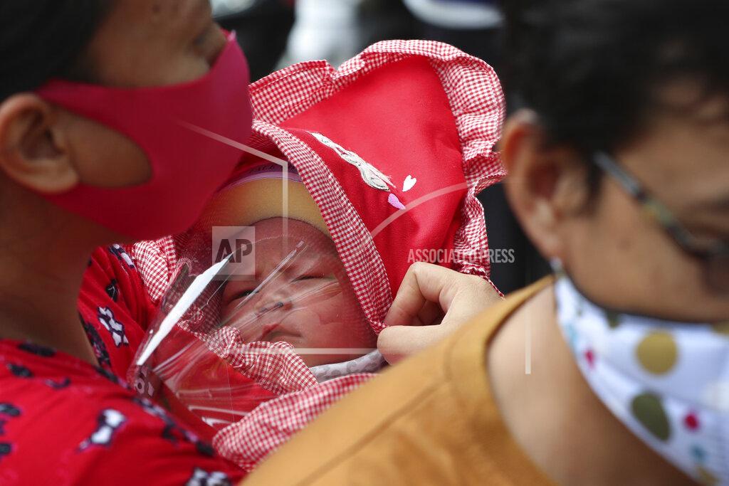 Achmad Ibrahim A mother carries her baby with face shield at a hospital in Jakarta, Indonesia, Tuesday, April 28, 2020. The world's Muslims have begun Ramadan with dawn-to-dusk fasting amid restrictions imposed to slow the pandemic that left many confined to their homes and public venues like parks, malls and even mosques are shuttered. (AP Photo/Achmad Ibrahim)