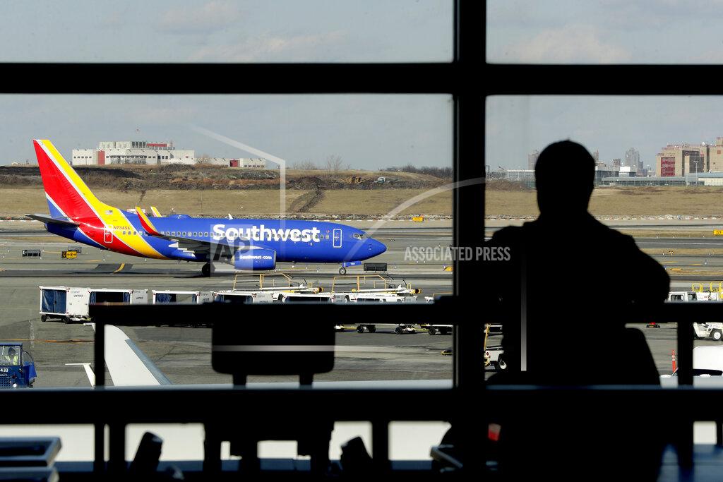 FILE- In this Jan. 25, 2019, file photo a Southwest Airlines jet moves on the runway as a person eats at a terminal restaurant at LaGuardia Airport in New York. The National Transportation Safety Board is meeting Tuesday, Nov. 19 in Washington to consider the cause of a deadly engine failure on a Southwest Airlines flight last year. The incident killed a passenger who was blown partly out of the plane when a piece of the engine shattered the window next to her. (AP Photo/Julio Cortez, File)