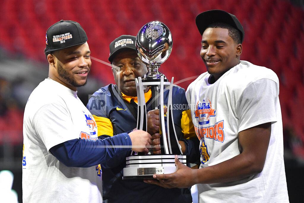 John Amis North Carolina A&T quarterback and offensive player of the game Kylil Carter, left, coach Sam Washington, and defensive player of the game linebacker Jacob Roberts, right, hold the trophy after the Celebration Bowl NCAA college football game against Alcorn State, Saturday, Dec. 21, 2019, in Atlanta. North Carolina A&T won 64-44. (John Amis/Atlanta Journal-Constitution via AP)
