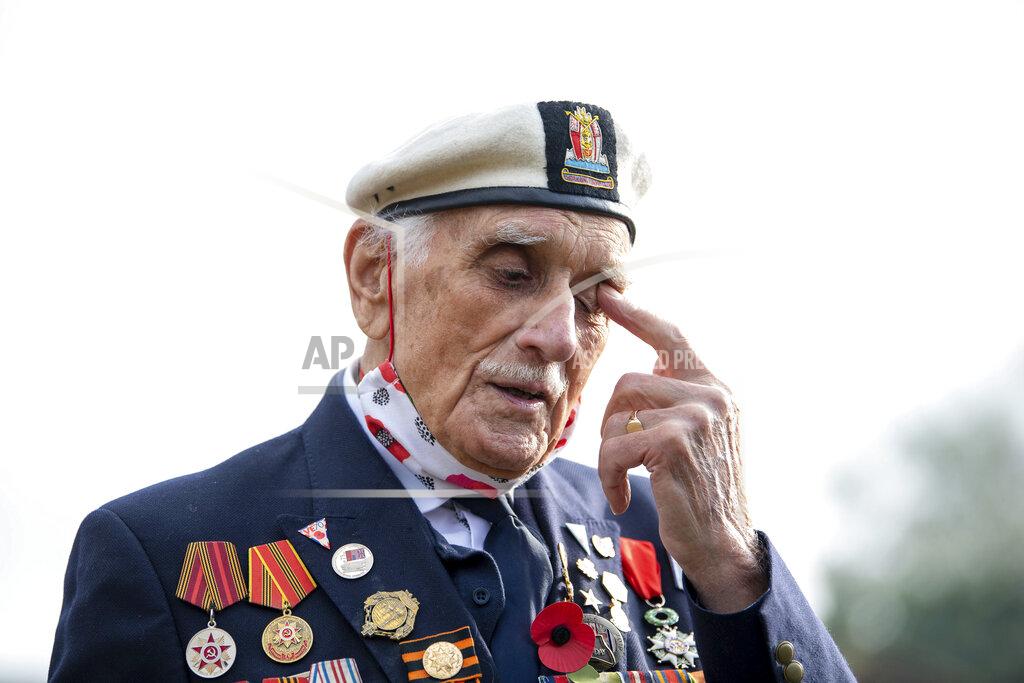 Joe Giddens Seymour 'Bill' Taylor, 95, from Colchester, who served as an Able Seaman in the Royal Navy onboard HMS Emerald during the D-Day landings joins neighbours in the street to observe the two minutes silence to pay his respects on Remembrance Sunday, in Essex, England, Sunday, Nov. 8, 2020. (Joe Giddens/PA via AP)