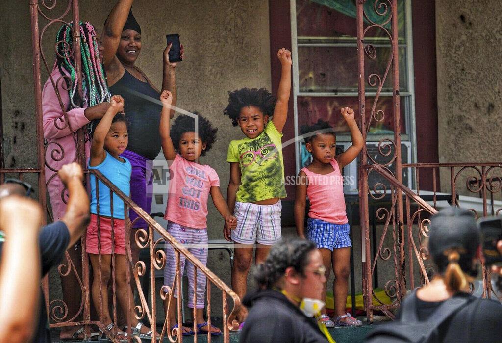 Martha Asencio-Rhine FILE- In this May 31, 2020, file photo, a family shows their support for a Black Lives Matter march as it passes by their home in Tampa, Fla. Protestors took to the streets of Tampa to protest the death of George Floyd, who died May 25 after he was pinned at the neck by a Minneapolis police officer. (Martha Ascencio-Rhine/Tampa Bay Times via AP, File)