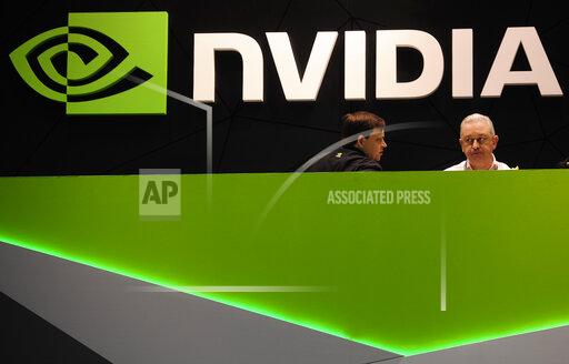 FILE - In this Thursday, Feb. 27, 2014 file photo, people gather in the Nvidia booth at the Mobile World Congress mobile phone trade show in Barcelona, Spain. European Union regulators opened an in-depth investigation Wednesday, Oct. 27, 2021 into graphics chip maker Nvidia’s $40 billion purchase of chip designer Arm over concerns it would limit competition, adding to global scrutiny of the deal. (AP Photo/Manu Fernandez, file)