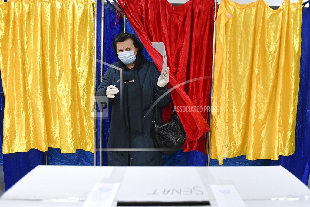 Andreea Alexandru A woman exits a voting cabin in Bucharest, Romania, Sunday, Dec. 6, 2020. Voting started in Romania's legislative election expected to restore some measure of stability after five years of political and social turbulence with more than 18 million Romanians registered to vote for a new legislative body. (AP Photo/Andreea Alexandru)