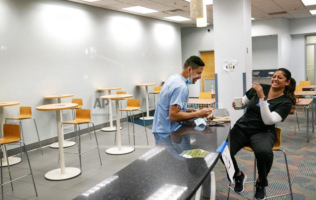 David Goldman Registered traveling nurses Subrina Geer, right, and husband, Edward Rojas, of New York City, relax during a coffee and cake break while working at a field hospital set up to handle a surge of COVID-19 patients, Wednesday, Feb. 10, 2021, in Cranston, R.I. The couple saw the disease ravage New York City hospitals last year. This is different: "It was a breath of fresh air to see how many patients we could discharge," Geer said. "It's a thrill in a way compared to what I saw in New York." (AP Photo/David Goldman)