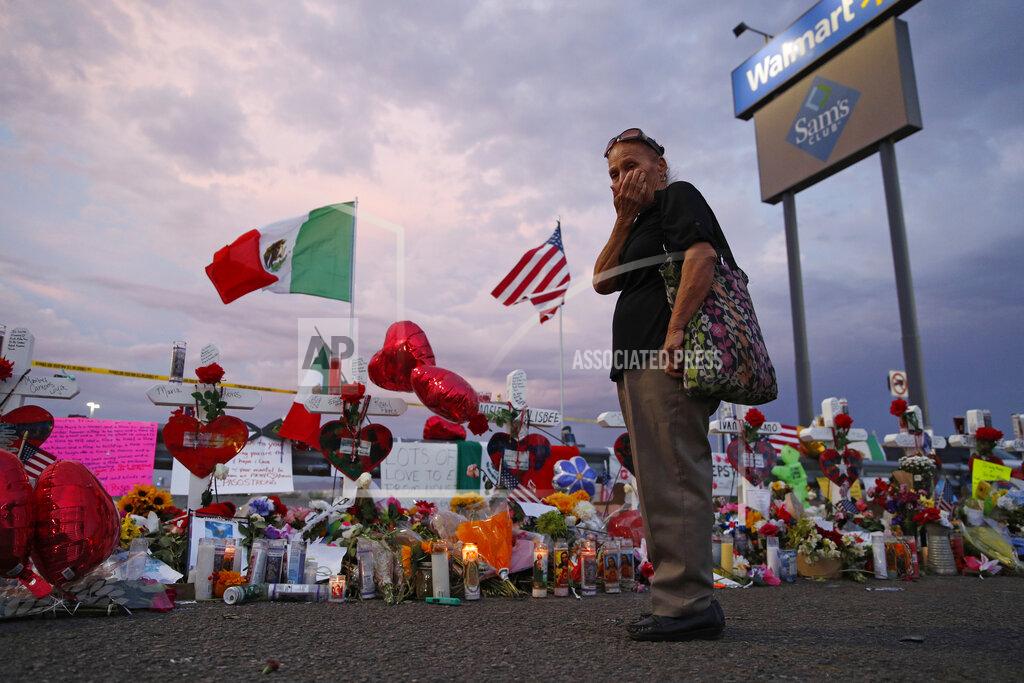John Locher FILE - In this Aug. 6, 2019 file photo, Catalina Saenz wipes tears from her face as she visits a makeshift memorial near the scene of a mass shooting at a shopping complex in El Paso, Texas. El Paso is marking the year anniversary of the a shooting at a crowded Walmart by remembering the 23 people killed. Authorities have said the gunman traveled from his home near Dallas to target Latinos in the Texas border city on Aug. 3, 2019. (AP Photo/John Locher, File)