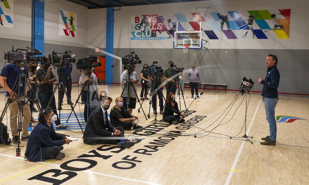 Damian Dovarganes California Gov. Gavin Newsom, right, takes questions from the media after a visit to Ramona Gardens Recreation Center in Los Angeles to discuss the state's efforts to vaccinate hard-to-reach and disproportionately impacted communities, Sunday, Feb. 21, 2021. California's new system of delivering and scheduling coronavirus vaccines is being rolled out in select counties. It's the first step in Newsom's plan to smooth out what has been a disjointed vaccine rollout hampered by limited national supply. (AP Photo/Damian Dovarganes)