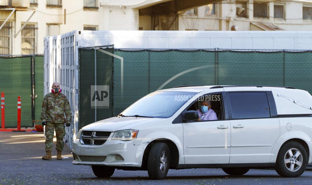 Damian Dovarganes A member of the California National Guard stands next to refrigerated trailers as a funeral hearse driver exits the department of the Los Angeles County Coroner in Los Angeles, Monday, Jan. 11, 2021. The coronavirus death toll in California reached 30,000 on Monday, another staggering milestone as the nation's most populous state endures the worst surge of the nearly yearlong pandemic. (AP Photo/Damian Dovarganes)