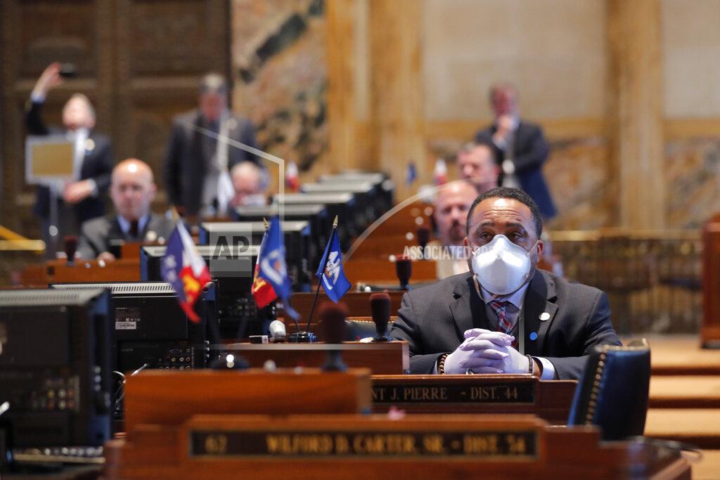Gerald Herbert FILE - In this March 31, 2020 file photo, State Rep. Vincent Pierre, D-Dist. 44, wears a mask and gloves as legislators convene in a limited number while exercising social distancing, due to the new coronavirus pandemic, at the state Capitol in Baton Rouge, La. Where political divides marred early recovery efforts after Hurricane Katrina in 2005, Louisiana is showing rare political unity in the fight against the new coronavirus. (AP Photo/Gerald Herbert, File)