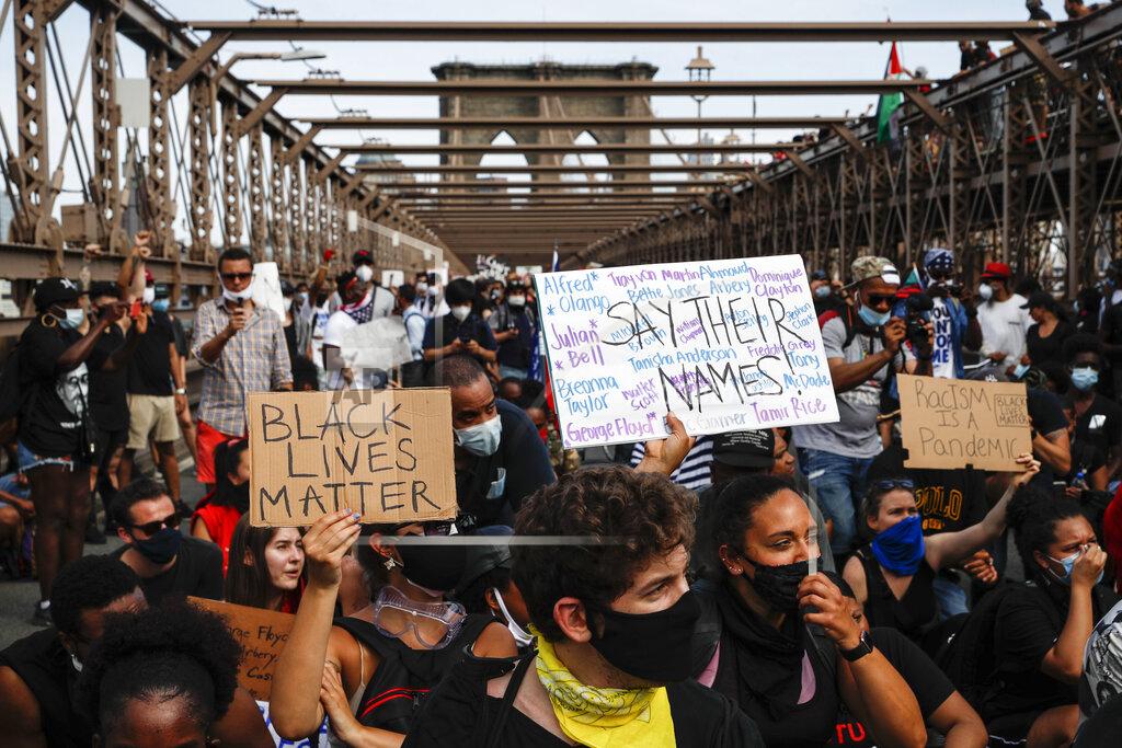 John Minchillo Protesters take a knee before continuing their march on the Brooklyn Bridge after attending a memorial service for George Floyd, on Thursday, June 4, 2020, in the Brooklyn borough of New York. Floyd, an African American man, died on May 25 after a white Minneapolis police officer pressed a knee into his neck for several minutes even after he stopped moving and pleading for air. (AP Photo/John Minchillo)