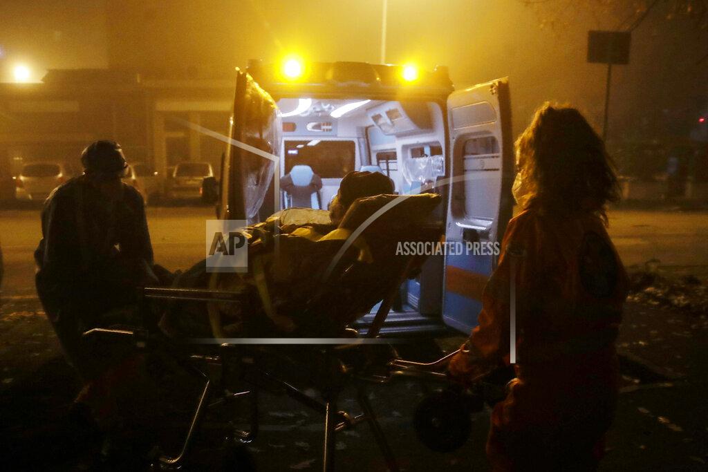 Medical volunteer Beatrice Ammattatiello, right and medical staffer Paolo Pozzoli carry a suspected Covid patient out of an apartment building during their shift with the emergency White Cross ambulance, in Cinisello Balsamo, near Monza, Italy, Thursday, Nov. 19, 2020. The city of Monza north of Milan is best known for its Formula 1 racetrack. In 2020, it has been the ambulance service that has been doing most of the racing. Over three days that an Associated Press photographer traveled on night calls with an ambulance service, the Monza-Brianza province of some 875,000 bordering Milan added 2,500 new cases, part of Italy’s new epicenter in the Lombardy region. (AP Photo/Luca Bruno)