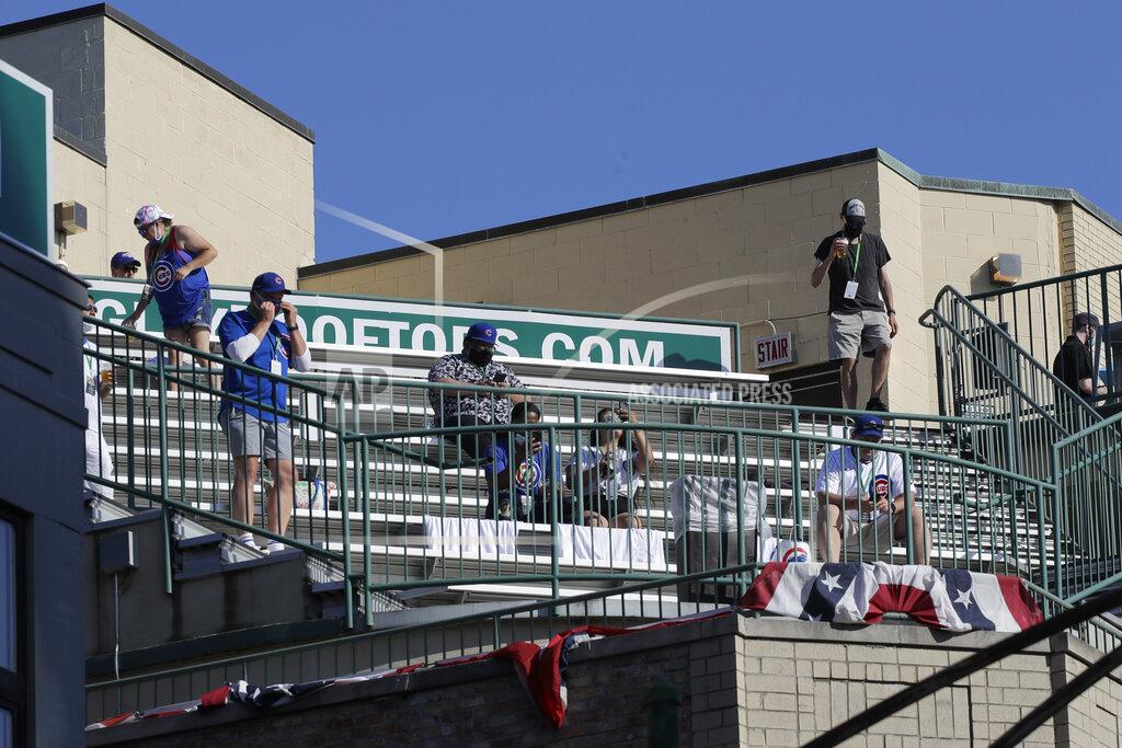Nam Y. Huh Chicago Cubs fans look to the field from a nearby rooftop before an opening day baseball game between the Chicago Cubs and the Milwaukee Brewers in Chicago, Friday, July 24, 2020, in Chicago. For fans looking to see major league baseball live during the coronavirus pandemic, there are few options besides the rooftops along Waveland and Sheffield Avenues. (AP Photo/Nam Y. Huh)
