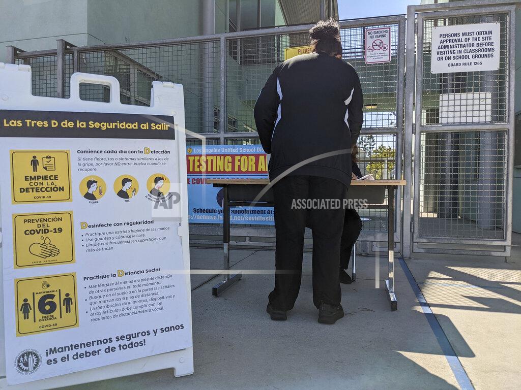 Damian Dovarganes In this Tuesday, March 16, 2021, photo, parents pick up school materials outside the Aurora Elementary School in Los Angeles. Students in California classrooms can sit 3 feet apart instead of 6 under new guidelines adopted by the state as school officials figure out how to reopen campuses closed for a year during the coronavirus pandemic. (AP Photo/Damian Dovarganes)