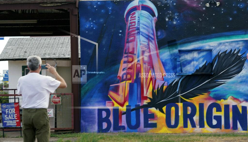 Lm Otero Gene Walker, of Denison, Texas, makes a photo of a Blue Origin mural on a building for sale in Van Horn, Texas, Tuesday Oct. 12, 2021. Today's launch has been pushed to Wednesday due to weather. (AP Photo/LM Otero)