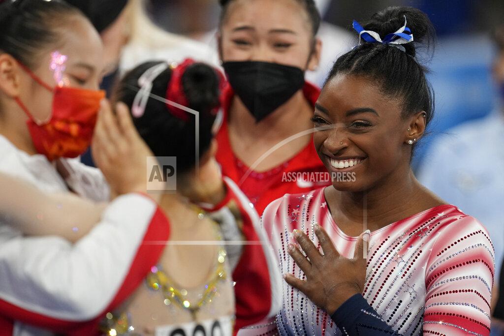 Natacha Pisarenko Simone Biles, of the United States, smiles as Tang Xijing, of China, left, embraces teammate Guan Chenchen after the latter won the gold medal on the balance beam during the artistic gymnastics women's apparatus final at the 2020 Summer Olympics, Tuesday, Aug. 3, 2021, in Tokyo, Japan. Biles won the bronze medal. (AP Photo/Natacha Pisarenko)