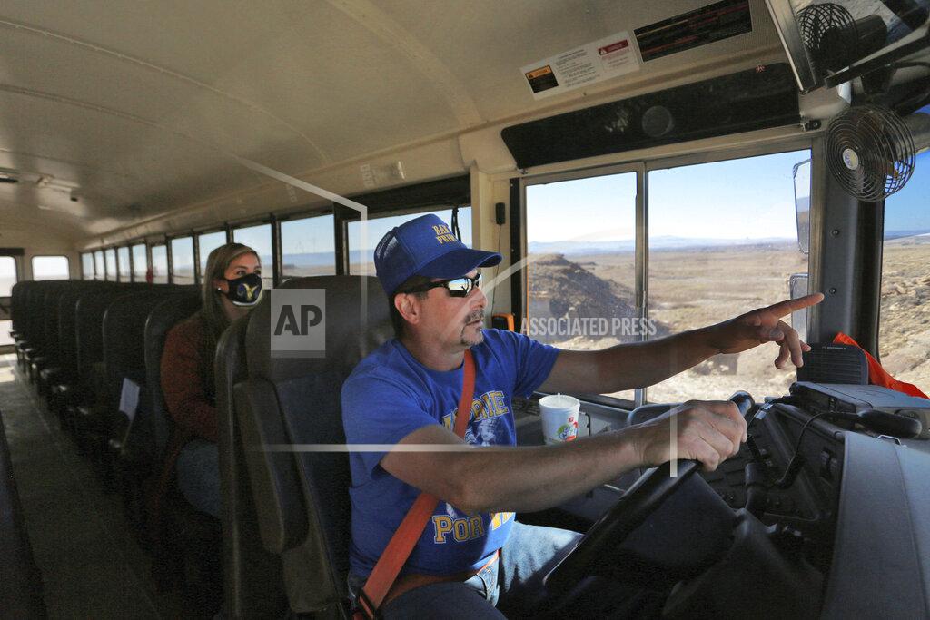 Cedar Attanasio School bus driver by Kelly Maestas travels along a dirt road, with social worker Victoria Dominguez, outside Cuba, N.M., Oct. 19, 2020. The switch to remote learning in rural New Mexico has left some students profoundly isolated — cut off from others and the grid by sheer distance. The school system is sending school buses to students’ far-flung homes to bring them assignments, meals and a little human contact. (AP Photo/Cedar Attanasio)