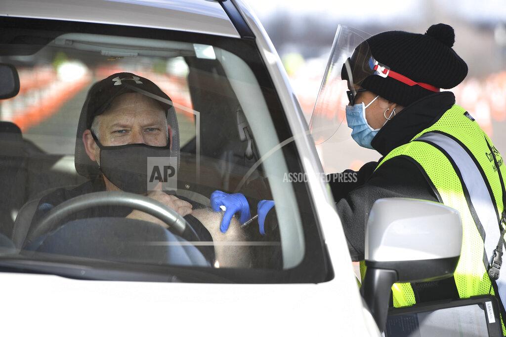 Jessica Hill Educator John Cormier of Norwich, Conn., receives a shot from LPN Lizmary Reyes, right, on opening day of the Connecticut's largest COVID-19 Vaccination Drive-Through Clinic Monday, Jan. 18, 2021, in East Hartford, Conn. The former Pratt & Whitney Runway has been converted into a ten-lane, drive-through COVID-19 Mass Vaccination Clinic, with the Pfizer-BioNTech vaccine being administered by Community Health Center, Inc. (CHC). Vaccinations are by appointment only to eligible individuals in Phase 1a and 1b through Connecticut's 211 system or the CDC's Vaccine Administration Management System. (AP Photo/Jessica Hill)
