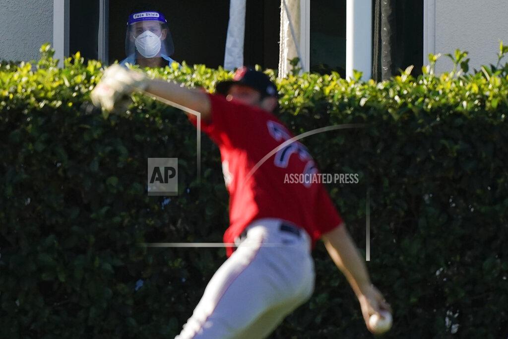 Brynn Anderson Boston Red Sox pitcher Jay Groome (77) throws the ball as a medical worker with a face shield near a testing site watches the players during spring training baseball practice on Monday, Feb. 22, 2021, in Fort Myers, Fla. (AP Photo/Brynn Anderson)