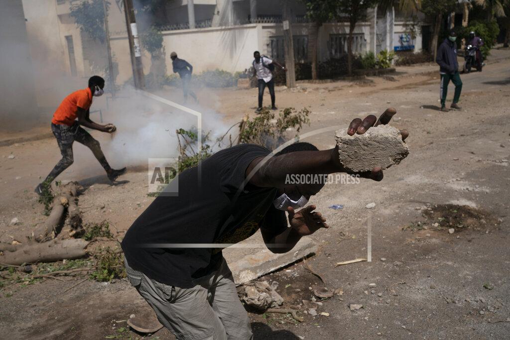 Leo Correa A supporter of the politician Ousmane Sonko holds a rock during clashes with the police in Dakar, Senegal, Monday, Feb. 8, 2021. Deadly protests have erupted in the West African nation of Senegal, long considered a bastion of democracy and a regional leader on diplomacy issues. (AP Photo/Leo Correa)