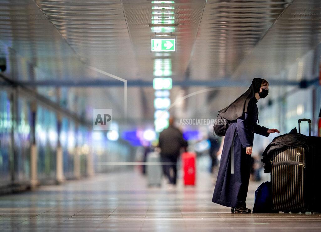 Michael Probst A nun wearing a face mask stands next to her baggage at the airport in Frankfurt, Germany, Tuesday, March 30, 2021. (AP Photo/Michael Probst)