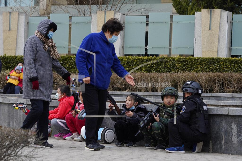 Ng Han Guan Minders look after children at play in Beijing on Tuesday, Feb. 23, 2021. China's population grew last year, the government said Thursday, April 29, 2021 following a news report a once-a-decade census might have found a decline, possibly adding to downward pressure on economic growth. (AP Photo/Ng Han Guan)