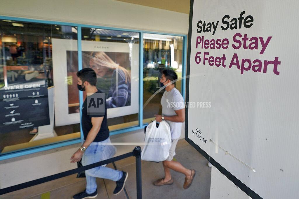 Chris O'meara Shoppers wear protective face masks as they walk past a social distancing sign at the Ellenton Premium Outlet stores Friday, Nov. 27, 2020, in Ellenton, Fla. Attendance at the mall was down in an attempt to avoid spreading the corona virus. (AP Photo/Chris O'Meara)