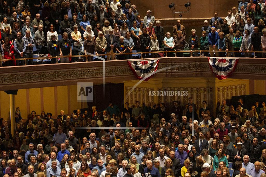 Rebecca Droke The crowd stands as the colors are presented to open the one-year commemoration of the Tree of Life synagogue attack at Soldiers & Sailors Memorial Hall and Museum, Sunday, Oct. 27, 2019, in Pittsburgh. A year ago, a gunman entered the Tree of Life synagogue and killed 11 members of three congregations, Dor Hadash, New Light and Tree of Life/Or L'Simcha, holding Shabbat services in the building. (AP Photo/Rebecca Droke)
