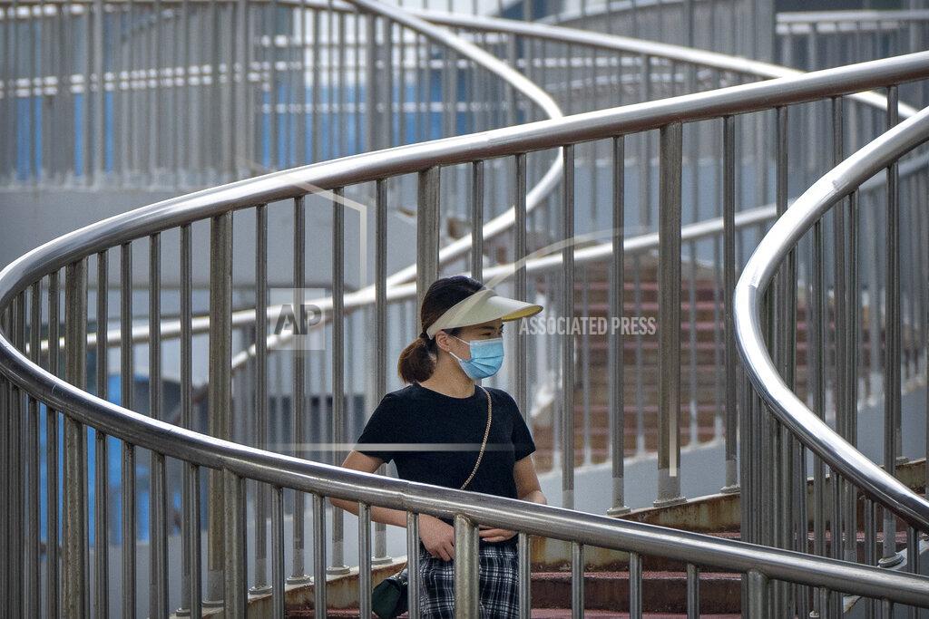 Mark Schiefelbein A woman wearing a face mask to protect against COVID-19 walk across a pedestrian bridge during the morning rush hour in Beijing, Wednesday, Aug. 4, 2021. China's worst coronavirus outbreak since the start of the pandemic a year and a half ago escalated Wednesday with dozens more cases around the country, the sealing-off of one city and the punishment of its local leaders. (AP Photo/Mark Schiefelbein)