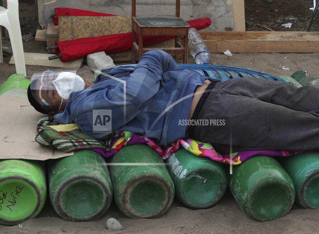 Martin Mejia A man sleeps on top of empty oxygen cylinders, waiting for a shop to open to refill his tank, in the Villa El Salvador neighborhood of Lima, Peru, early Thursday morning, Feb. 18, 2021. A crisis over the supply of medical oxygen for coronavirus patients has struck nations in Africa and Latin America, where warnings went unheeded at the start of the pandemic and doctors say the shortage has led to unnecessary deaths. (AP Photo/Martin Mejia)