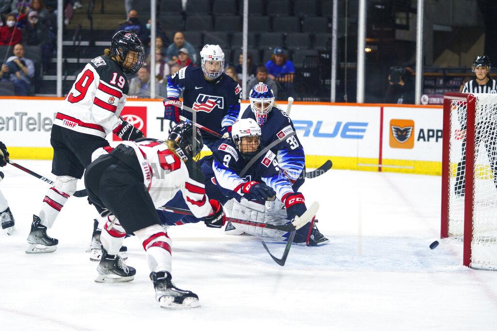Chris Szagola Canada's Sarah Fillier, left, shoots the puck past United States' Megan Bozek, center, and Alex Cavallini, right, for a goal during the first period of a hockey game Friday, Oct. 22, 2021, in Allentown, Pa. (AP Photo/Chris Szagola)