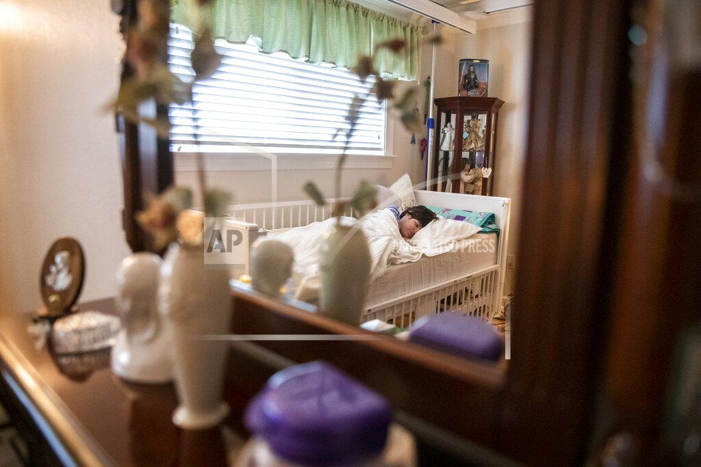 Sophia Germer Lauren, the daughter of Sue Roesky who has cerebral palsy and is non-verbal, lies in bed at their home in Metairie, La., Friday, Sept. 17, 2021. (Sophia Germer/The Times-Picayune/The New Orleans Advocate via AP)