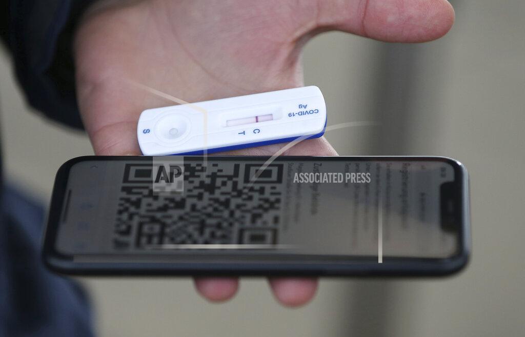 Ronald Zak A man shows a negative COVID-19 test together with his cellphone QR code in a set up for rapid new coronavirus testing in Vienna, Austria, Monday, Nov. 30, 2020. The Austrian government has moved to restrict freedom of movement for people, in an effort to slow the onset of the COVID-19 disease and the spread of the coronavirus. (AP Photo/Ronald Zak)