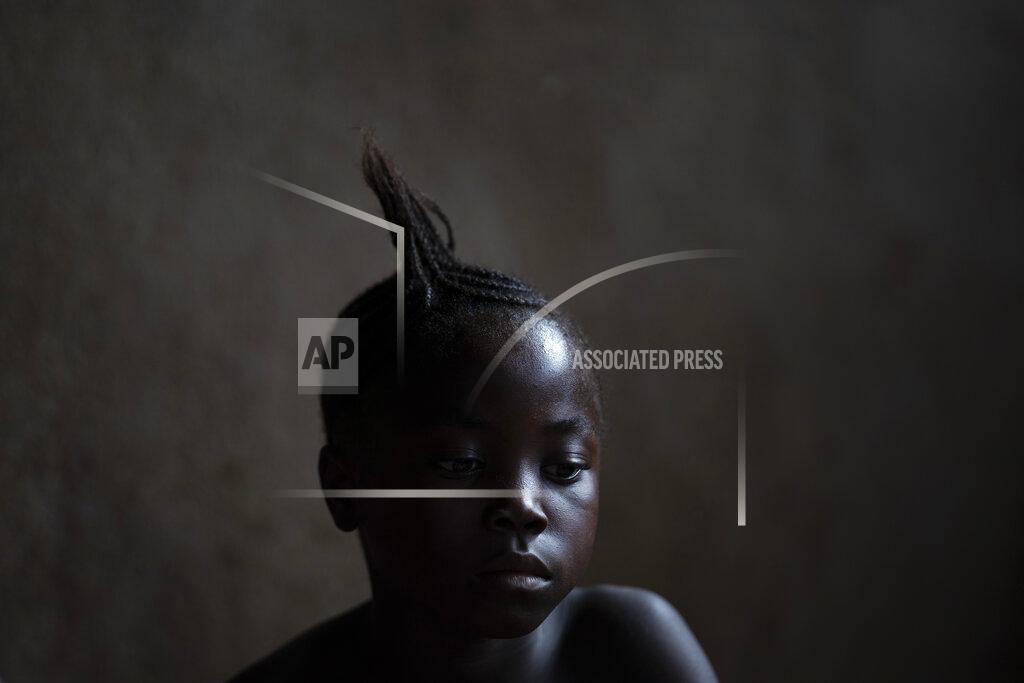 Leo Correa A girl watches a video clip on a portable DVD player in Komao village, outskirts of Koidu, district of Kono, Sierra Leone, Sunday, Nov. 22, 2020. (AP Photo/Leo Correa)