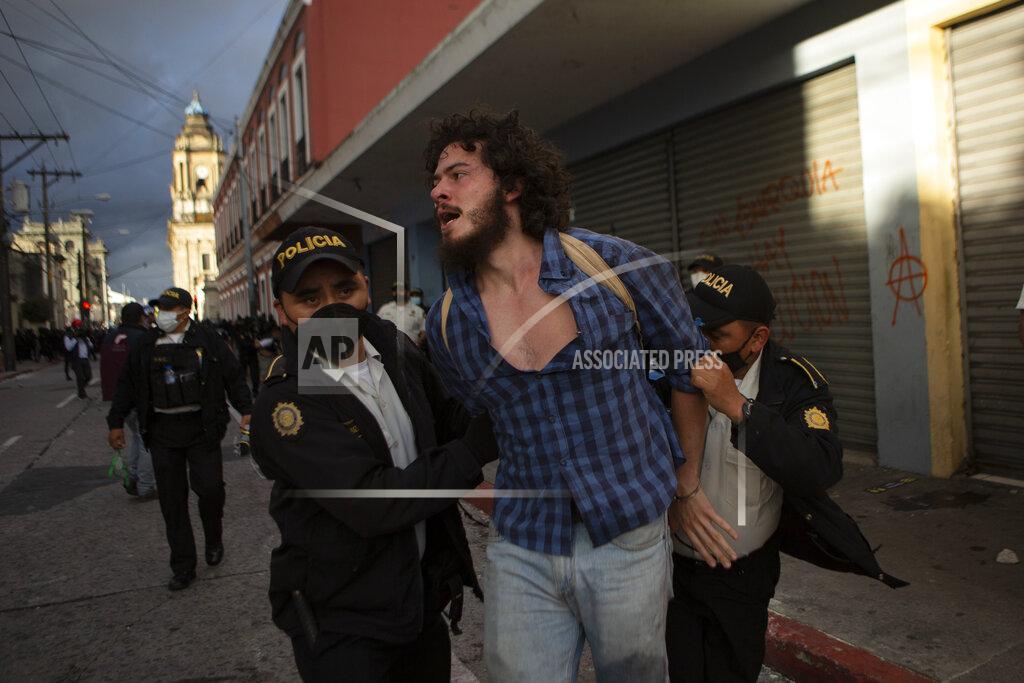 Oliver De Ros A man is detained by police near the Congress building after protesters set a part of the building on fire, in Guatemala City, Saturday, Nov. 21, 2020. Hundreds of protesters were protesting in various parts of the country Saturday against Guatemalan President Alejandro Giammattei and members of Congress for the approval of the 2021 budget that reduced funds for education, health and the fight for human rights. (AP Photo/Oliver De Ros)