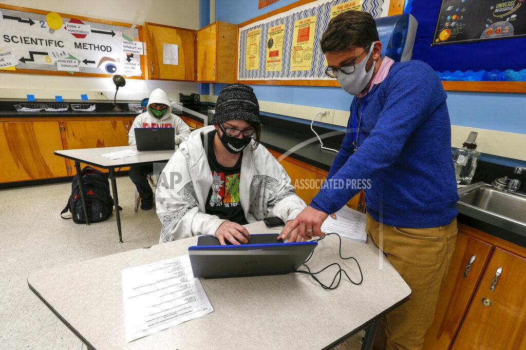 Bobby Smith gets some help opening a PowerPoint on volcanoes from QHS teacher Jared Holman at Quincy High School, Wednesday, Nov. 4, 2020. in Quincy, Ill., Wednesday, Nov. 4, 2020. (Jake Shane/Quincy Herald-Whig via AP)