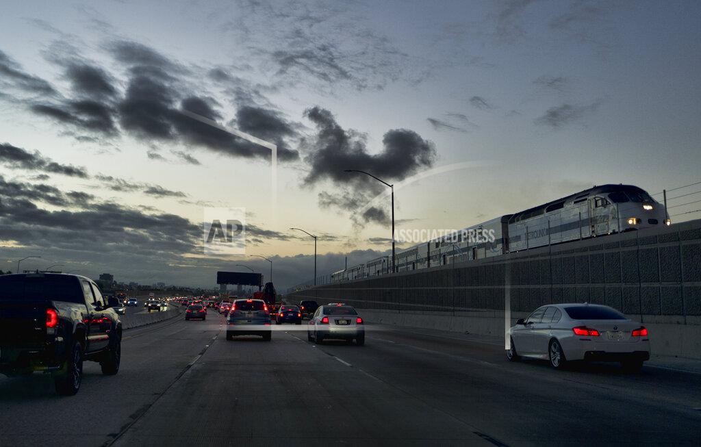 Richard Vogel FILE - In this Oct. 4, 2018 file photo a Metrolink train passes as early morning commuters drive south down Interstate 5 in Los Angeles. Train service was halted Thursday, Sept. 16, 2021, for the next two weeks as crews shore up unstable ground along cliffside railroad tracks in Southern California. The planned closure between the Laguna Niguel//Mission Viejo station in southern Orange County and the Oceanside stop in northern San Diego County is expected to last until Oct. 3. "Between the sea, the sand and the earth, there has been some movement of the railroad tracks" in southern San Clemente, Metrolink spokesperson Paul Gonzales said. (AP Photo/Richard Vogel,File)