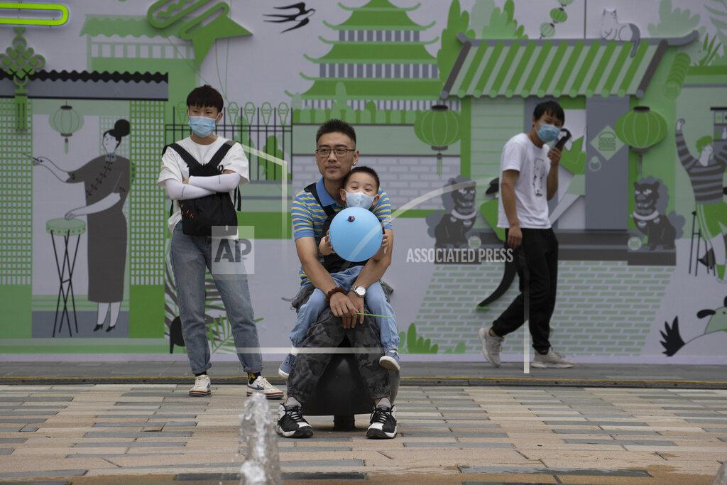 Ng Han Guan A man holds a child wearing a mask to curb the spread of the coronavirus as they watch a water fountain on Children's Day in Beijing on Monday, June 1, 2020. (AP Photo/Ng Han Guan)