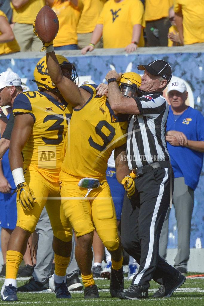 Craig Hudson West Virginia safety Jovanni Stewart (9) is briefly caught in a referee's microphone wire after retrieving a fumble during the second half of an NCAA college football game against Kansas in Morgantown, W. Va., Saturday Oct. 6, 2018. (Craig Hudson/Charleston Gazette-Mail via AP)