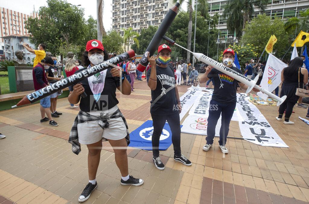 Andre Penner Demonstrators holding fake guns shaped like pencils, and a syringe, attend a protest against Brazilian President Jair Bolsonaro and his handling of the pandemic and economic policies protesters say harm the interests of the poor and working class, in Cuiaba, Brazil, Saturday, June 19, 2021. (AP Photo/Andre Penner)