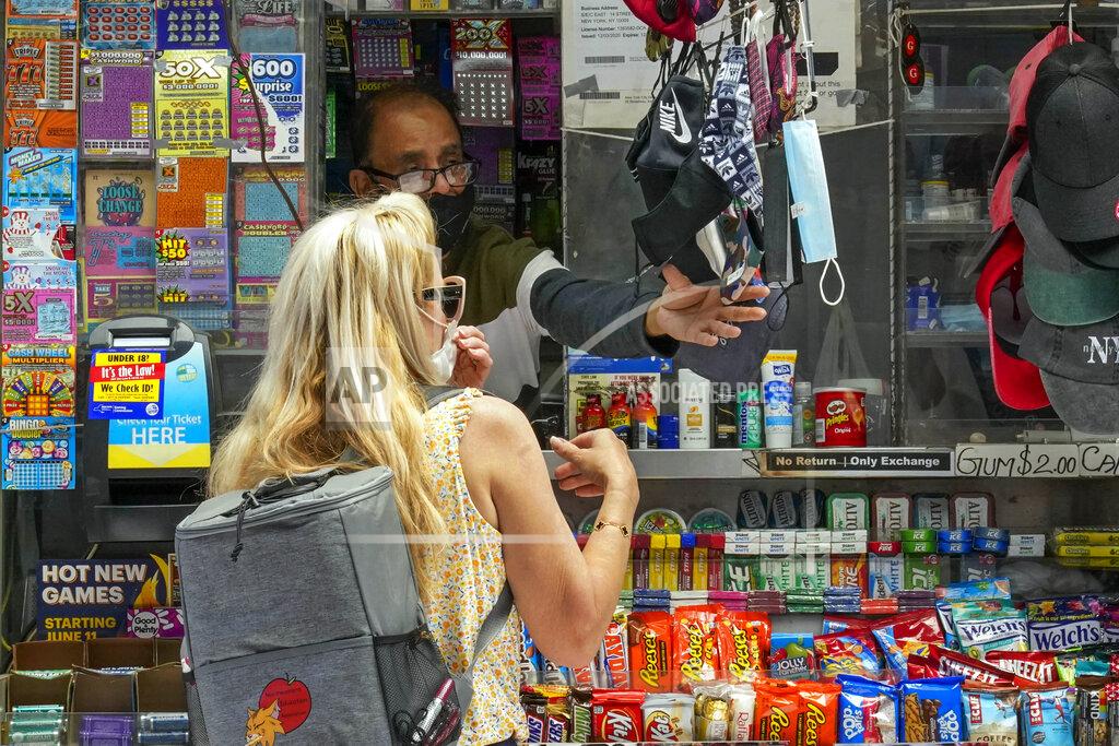 Mary Altaffer FILE — In this May 17, 2021 file photo, a woman buys a face mask at a newspaper stand in the East Village of New York. New York Gov. Andrew Cuomo and New York City Mayor Bill de Blasio have scheduled competing news conferences Monday, Aug. 2 amid rising COVID-19 case counts attributed to the highly contagious delta variant of the virus. (AP Photo/Mary Altaffer)