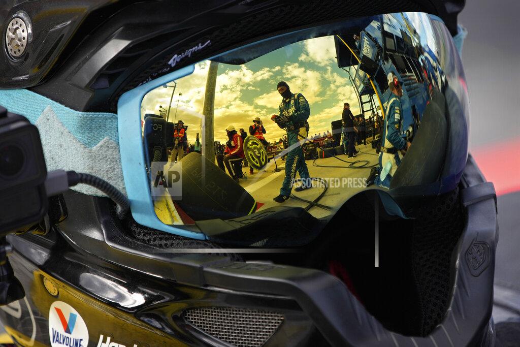 John Locher Pit crew members for driver Kyle Larson are reflected in a helmet during a NASCAR Cup Series auto race Sunday, March 6, 2022, in Las Vegas. (AP Photo/John Locher)