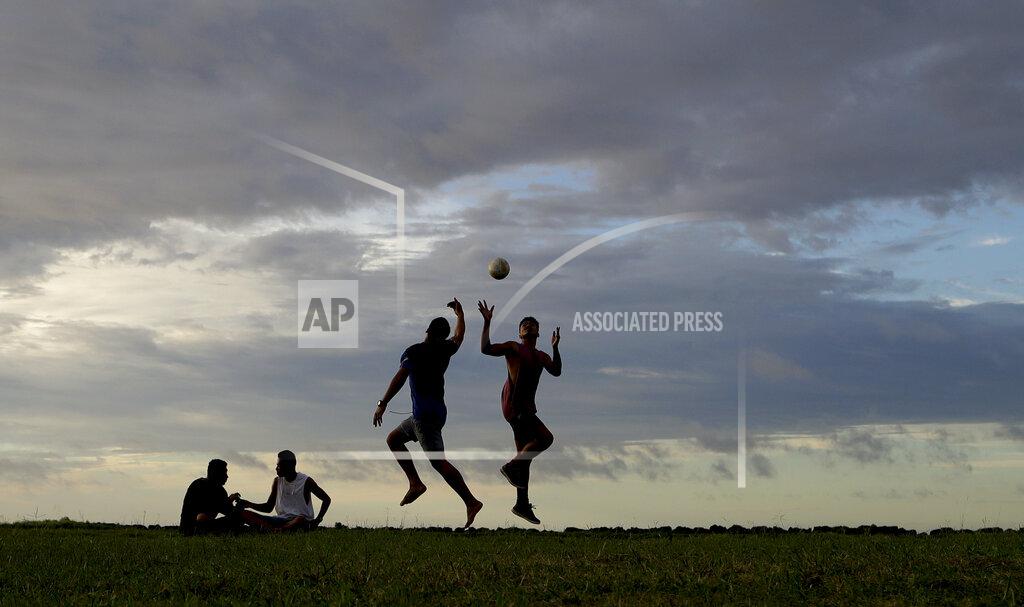 Mark Baker FILE - In this April 10, 2019, file photo, young men play a game of rugby at sunset in Nuku'alofa, Tonga. The largest cluster of places without the coronavirus can be found in the scattered islands of the South Pacific. Tonga, Kiribati, Samoa, Micronesia and Tuvalu are among those small nations yet to report a single case. But that doesn't mean they have been spared from the pandemic's effects. (AP Photo/Mark Baker, File)