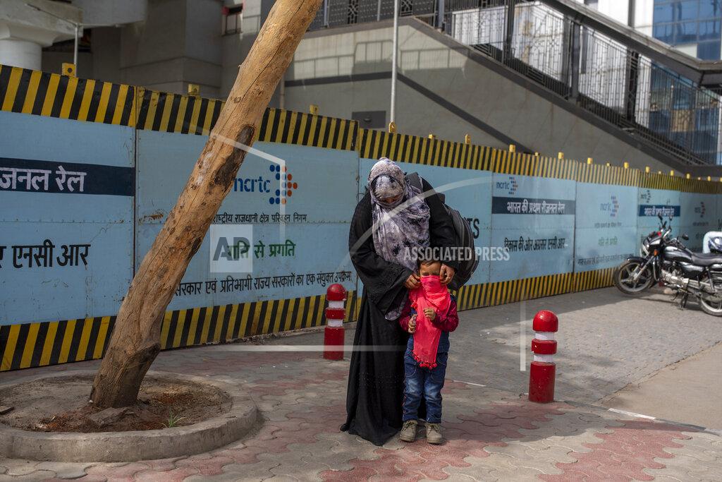Altaf Qadri A woman covers the face of her child with a scarf at a bus terminal in New Delhi, India, Wednesday, March 24, 2021. (AP Photo/Altaf Qadri)