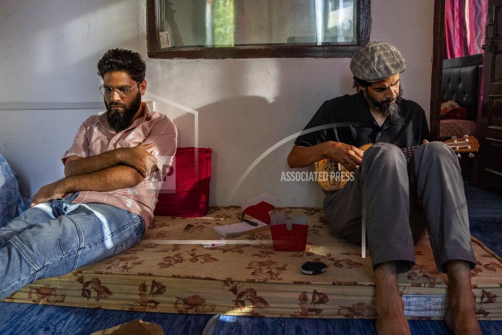 Dar Yasin Sarfaraz Javid, a Kashmiri musician and singer plays guitar as Arif Farooq, a rap singer sits nearby in a studio on the outskirts of Srinagar, Indian Kashmir, June 17, 2022. Musicians and artists in Kashmir are ordinary in life, each clutching onto the lived experiences of growing up in one of the world's most militarized zones that has known little but conflict for decades. But together, they embody a new form of music, a blend of progressive rock and hip hop that is an assertive expression of the region's political and cultural aspirations. (AP Photo/Dar Yasin)
